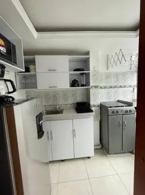 a kitchen with white cabinets and a sink and a refrigerator at Milano Manizales in Manizales