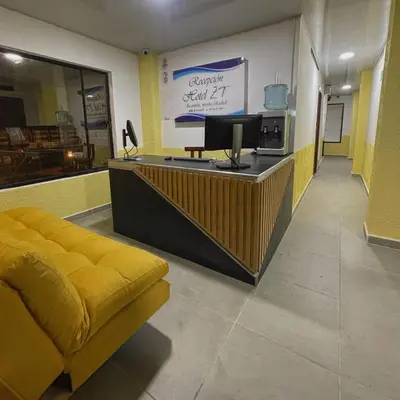 a lobby with a yellow couch and a tv on a counter at Hotel ZT in Mariquita