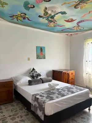 a bedroom with a bed with a painting on the ceiling at Casa Hotel Piedra del Sol in Betania