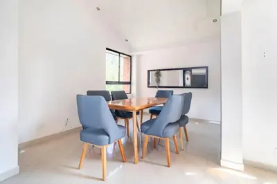 a dining room with a wooden table and blue chairs at 3 Story Penthouse with 2 parking spaces in Laureles in Medellín