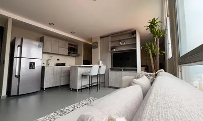 a living room with a white couch and a kitchen at Apartment near Provenza by Hoost in Medellín
