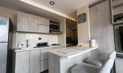 a kitchen with a counter with two chairs and a sink at Apartment near Provenza by Hoost in Medellín