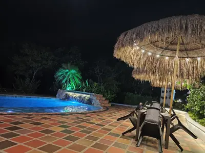 a patio with chairs and an umbrella next to a swimming pool at Finca La Casa de Pablo in Doradal
