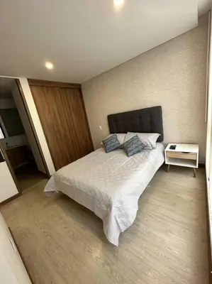 a bedroom with a large bed and a night stand at Loft moderno en zona exclusiva in Manizales