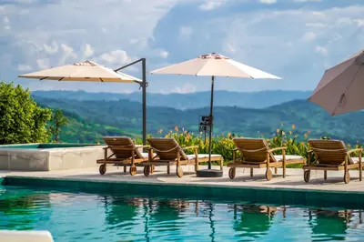 a group of chairs and umbrellas next to a swimming pool at Quinta San Felipe in Manizales
