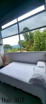a bed in a room with a large window at Villa Tikuna in Mariquita