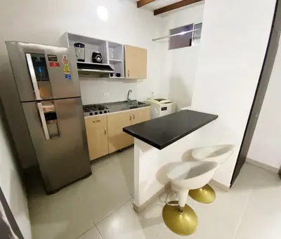 a small kitchen with a stainless steel refrigerator at Aparta Suites Rosales in Medellín
