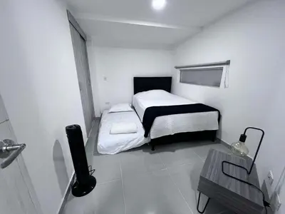 a small white bedroom with a bed and a table at Medellin's Coolest neighborhood in Medellín