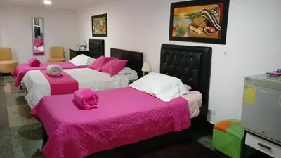 a room with three beds with pink covers on them at HOTEL GALICIA PLAZA in Manizales