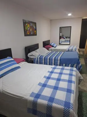 a room with three beds with blue and white sheets at HOTEL GALICIA PLAZA in Manizales