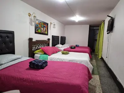 a room with three beds with pink and white sheets at HOTEL GALICIA PLAZA in Manizales
