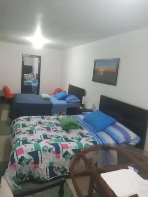 a bedroom with two beds and a table with a table at HOTEL GALICIA PLAZA in Manizales