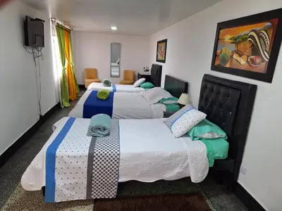 a bedroom with four beds and a flat screen tv at HOTEL GALICIA PLAZA in Manizales
