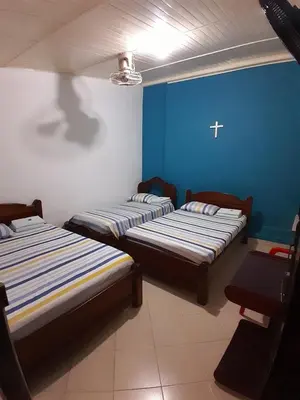 three beds in a room with a cross on the wall at Hotel Bruselas Mutata in Mutatá