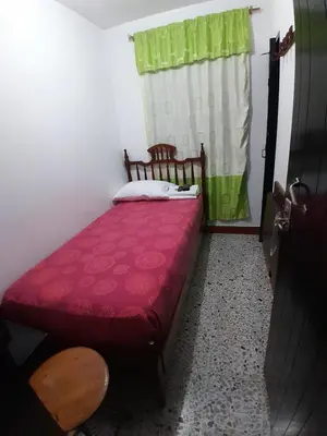 a small bed in a room with a red bedspread at Hotel Bruselas Mutata in Mutatá