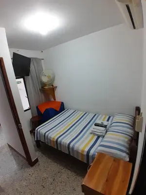 a small bedroom with a bed and a wooden table at Hotel Bruselas Mutata in Mutatá