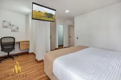 a bedroom with a bed and a television on the wall at Apartamento de lujo laureles con Aire y hamaca 200 in Medellín