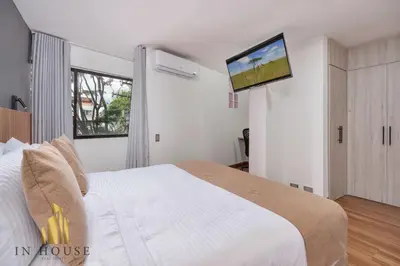 a bedroom with a bed and a tv on the wall at Apartamento de lujo laureles con Aire y hamaca 200 in Medellín