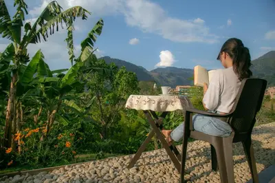 a woman sitting at a table with a cup of coffee at loft grupo y parejas AZUCENAS in Jardin