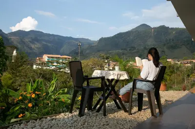 a woman sitting at a table with a view of mountains at loft grupo y parejas AZUCENAS in Jardin
