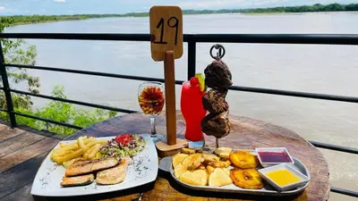 a table with a plate of food and a glass of wine at Hotel Tekal del Rio in Puerto Boyacá