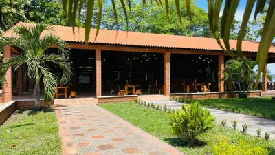 a building with tables and chairs in front of it at Hotel Tekal del Rio in Puerto Boyacá