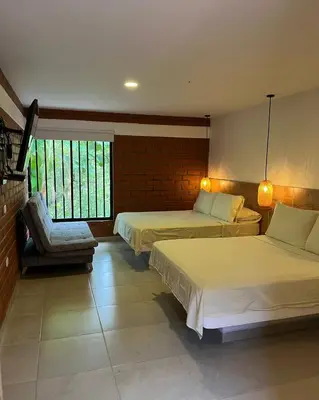 a hotel room with two beds and a chair at Hotel Tekal del Rio in Puerto Boyacá