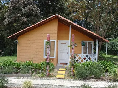 a small shed with a white door and flowers at Hospedaje Santaelena -chalets de montaña- in Santa Elena