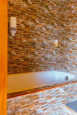 a bath tub in a bathroom with a stone wall at Suite Doble Especial in Jericó