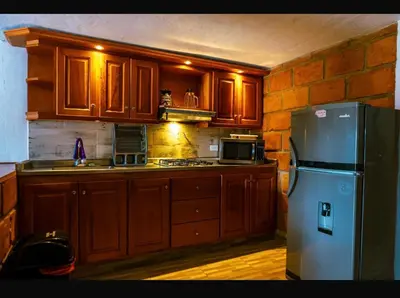 a kitchen with wooden cabinets and a stainless steel refrigerator at Suite Doble Especial in Jericó