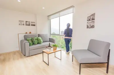 a woman standing in a living room looking out the window at NEW! Homey Loft El Tesoro-Fast Wifi in Medellín