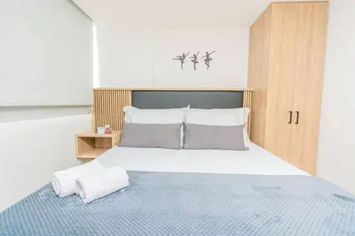 a bedroom with a large bed with white sheets and pillows at NEW! Homey Loft El Tesoro-Fast Wifi in Medellín