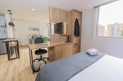 a bedroom with a bed and a desk with a television at NEW! Homey Loft El Tesoro-Fast Wifi in Medellín