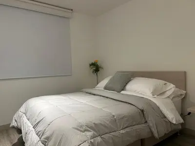 a white bedroom with a bed with a window at Apartamento Manizales II in Manizales