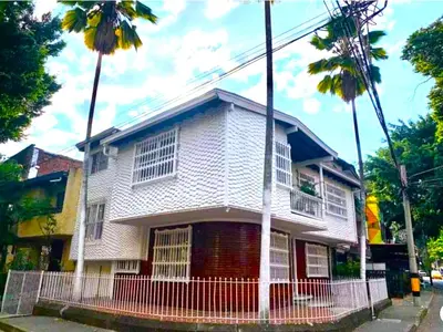 a white house with two palm trees in front of it at Accommodation HOUSETEL COCOON Medellin in Medellín