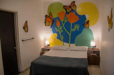 a bedroom with a bed with butterflies painted on the wall at La Familia Hostel - Manila in Medellín