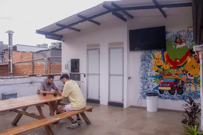 two men sitting at a picnic table in a room at La Familia Hostel - Manila in Medellín