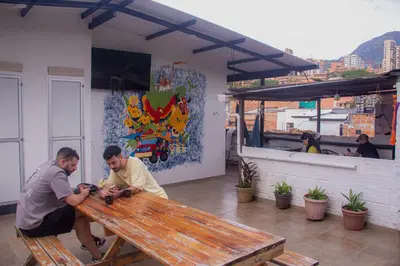 two men sitting at a wooden picnic table at La Familia Hostel - Manila in Medellín