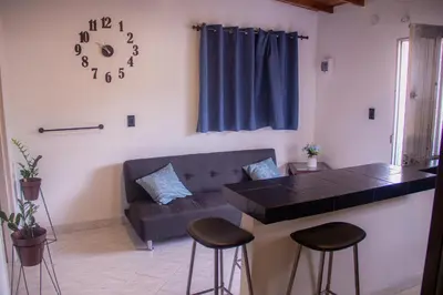 a living room with a couch and a table and stools at La Familia Hostel - Manila in Medellín