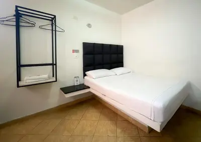 a bedroom with a large white bed and a mirror at Hotel Natural Medellin in Medellín