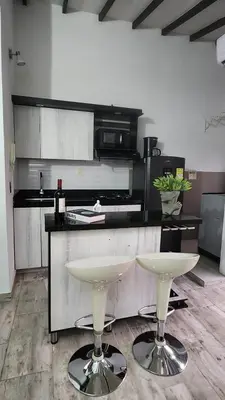 a kitchen with two white bar stools in front of a counter at moderno y nuevo aparta estudio en Laureles in Medellín