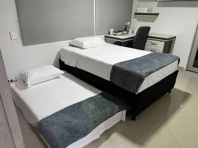 a room with two beds and a desk with a computer at Apto 4 habitaciones privadas 140mtros in Medellín