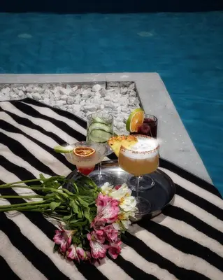 a tray with two cocktails and flowers next to a pool at Hotel Bella Isa in La Dorada