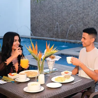 a man and a woman sitting at a table with food at Hotel Bella Isa in La Dorada