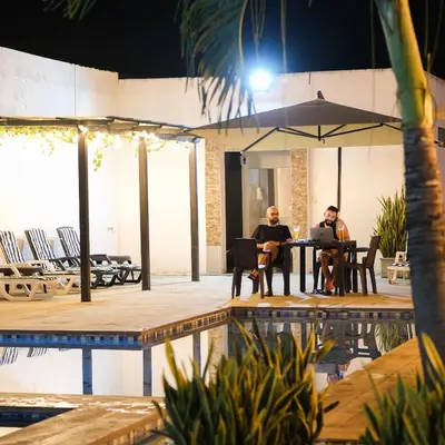two men sitting at a table next to a pool at Hotel Bella Isa in La Dorada