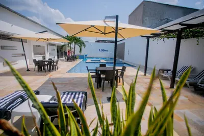 a swimming pool with tables and chairs and umbrellas at Hotel Bella Isa in La Dorada