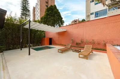 a patio with two chairs and an umbrella and a pool at Casa Penta Top Notch Villa in Medellín