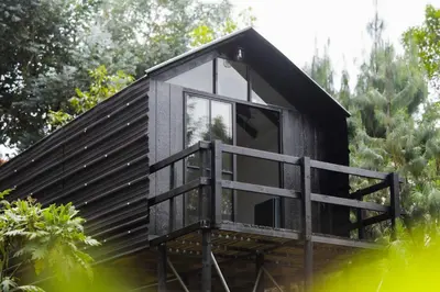 a small black cabin with a large window at Tiny House La Silleta in Medellín