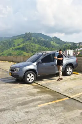 a man standing next to a car in a parking lot at Lindo y disponible Apartamento camino a termales in Manizales