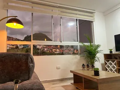a living room with a couch and a large window at Lindo y disponible Apartamento camino a termales in Manizales